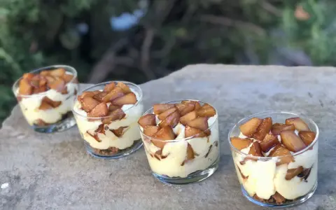 Quatre verrines mascarpone spéculoos, garnies de pommes caramélisées, sur une pierre.