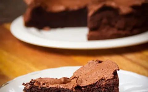 Une part de gâteau au chocolat intense, digne d'un chef pâtissier comme Pierre Hermé, sur une assiette blanche.
