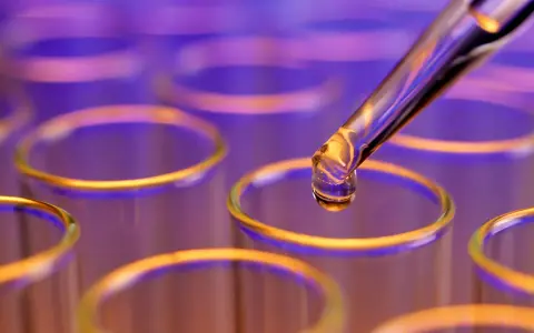 Goutte de colorant alimentaire liquide tombant d'une pipette dans un tube à essai.