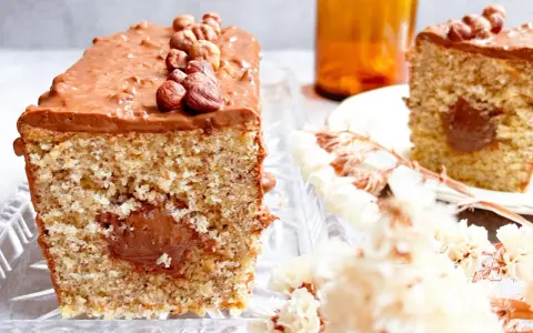 Gâteau moelleux avec un cœur coulant et un glaçage Nutella généreux, décoré de noisettes entières.