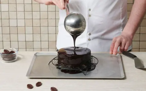 Un chef verse un glaçage au chocolat brillant sur un gâteau rond. Le glaçage sur gâteau froid ou chaud coule parfaitement, créant une finition miroir.
