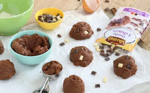 Pâte à cookies au chocolat prête à être façonnée. Des pépites de chocolat et un sachet "comment faire des pépites de chocolat" sont à proximité.