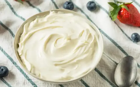 Un bol de crème mascarpone onctueuse, garni de fraises et de myrtilles, prêt à être dégusté.