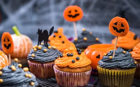 Cupcakes d'Halloween faciles décorés de glaçage orange et gris, de citrouilles et d'un chat noir. Parfait pour une fête effrayante !