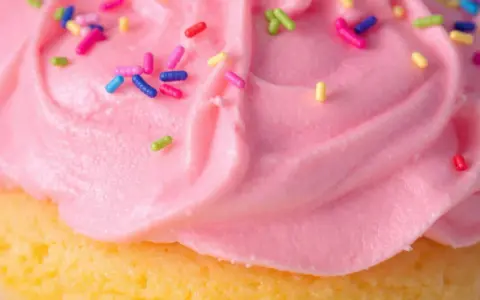 Glaçage cupcake sans beurre rose vif, parsemé de vermicelles colorés. Un délice léger et festif !
