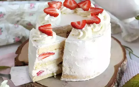 Un délicieux layer cake fraise, garni de crème fouettée et de fraises fraîches, prêt à être dégusté.