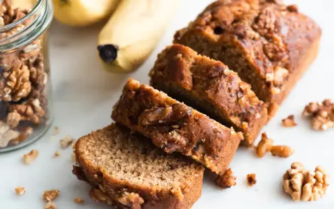 Tranches de délicieux dessert banane et noix, avec des bananes et des noix à proximité.
