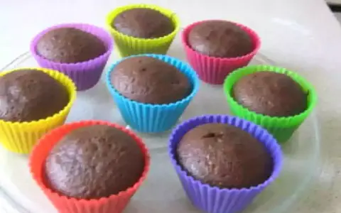 Huit cupcakes au chocolat, prêts à être dégustés, dans des moules colorés. Une recette de cupcake au chocolat facile et rapide.