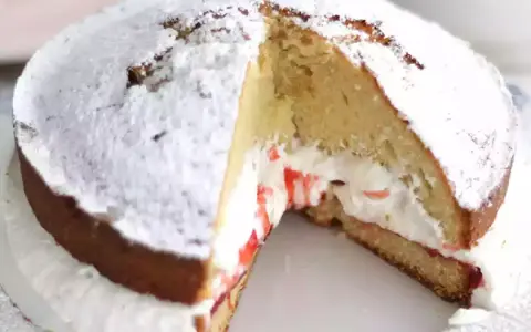 Un délicieux victoria cake, saupoudré de sucre glace, révèle sa garniture crémeuse et sa confiture de fruits rouges.
