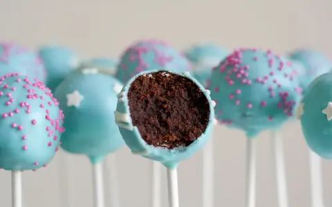 Gourmandes boules de chocolat bleu ciel, décorées de vermicelles roses ou d'étoiles blanches. Une recette facile de cake pop à dévorer !