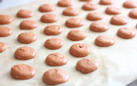 Des petites **collerettes macaron** marron clair, prêtes à être enfournées pour devenir de délicieux macarons.