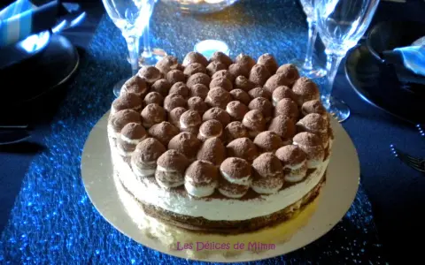 Un délicieux tiramisu revisité, parsemé de cacao, trône sur une table bleue scintillante, prêt à être dégusté.
