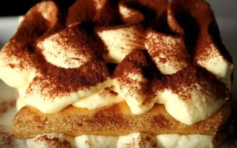 Un délicieux tiramisu au marsala, garni de cacao, avec des couches de crème onctueuse et de biscuits savoiardi.