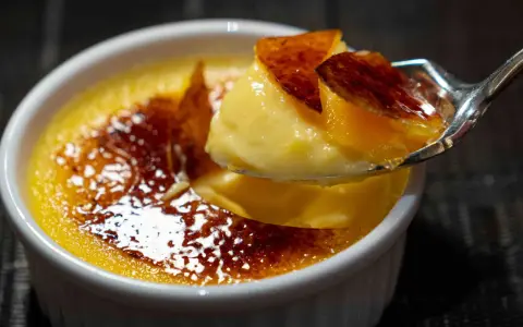 Une cuillère de crème brûlée, parfaite pour savoir que faire avec 4 jaunes d'œufs. La croûte caramélisée craque sous la cuillère.
