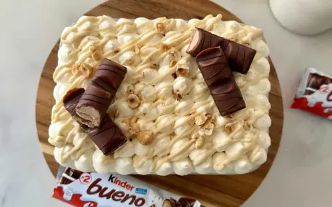 Un délicieux tiramisu Kinder Bueno, garni de morceaux de chocolat et de noisettes concassées. Un vrai régal pour les amateurs de chocolat !