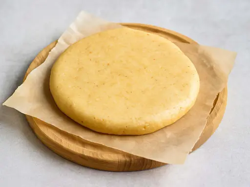 Pâte sablée crue, prête pour la conservation au frigo. Elle repose sur du papier sulfurisé, posé sur une planche en bois.