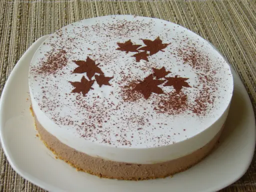 Gâteau bicolore, blanc et chocolat, décoré de feuilles d'automne en cacao. Un dessert léger et gourmand pour célébrer l'automne.