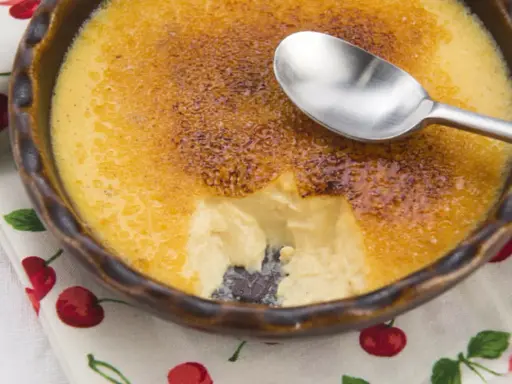 Crème brûlée avec une croûte caramélisée craquante. Une cuillère est posée sur le dessert, parfait pour une recette de crème brûlée facile et rapide.