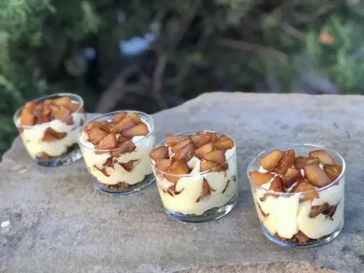 Quatre verrines mascarpone spéculoos, garnies de pommes caramélisées, sur une pierre.
