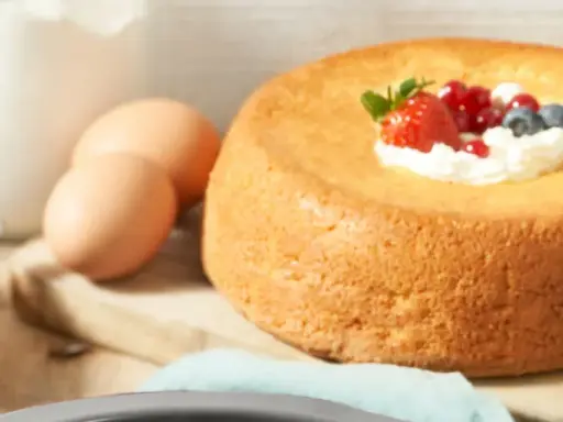 Un savarin traditionnel, doré et moelleux, garni de crème fouettée et de fruits rouges. Des œufs et de la farine sont prêts pour la préparation.