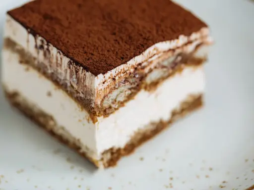 Une part de tiramisu onctueux, saupoudrée de cacao, prête à être dégustée. Une recette facile pour un dessert parfait.