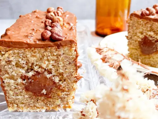Gâteau moelleux avec un cœur coulant et un glaçage Nutella généreux, décoré de noisettes entières.