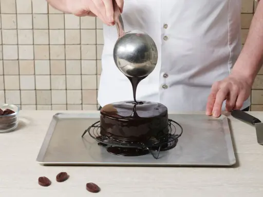 Un chef verse un glaçage au chocolat brillant sur un gâteau rond. Le glaçage sur gâteau froid ou chaud coule parfaitement, créant une finition miroir.