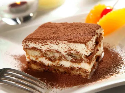 Un délicieux tiramisu, avec sa touche d'alcool subtile, saupoudré de cacao, prêt à être dégusté.