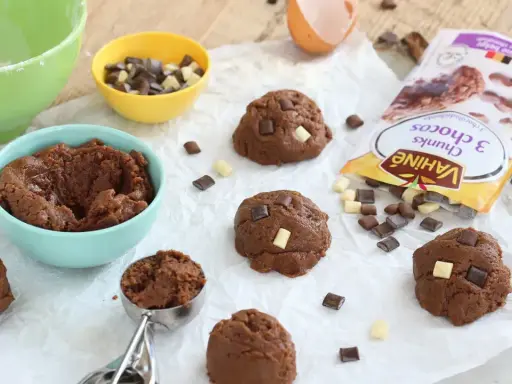 Pâte à cookies au chocolat prête à être façonnée. Des pépites de chocolat et un sachet "comment faire des pépites de chocolat" sont à proximité.