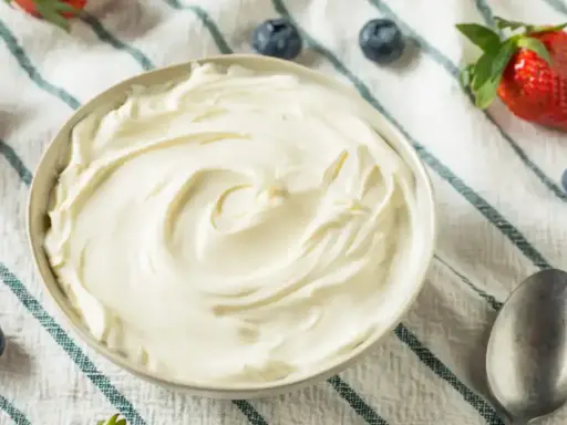 Un bol de crème mascarpone onctueuse, garni de fraises et de myrtilles, prêt à être dégusté.