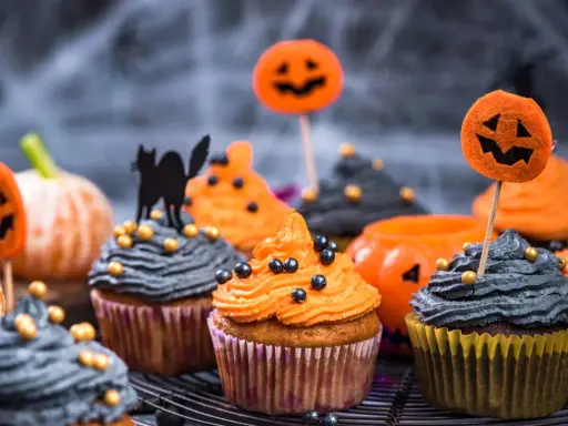Cupcakes d'Halloween faciles décorés de glaçage orange et gris, de citrouilles et d'un chat noir. Parfait pour une fête effrayante !
