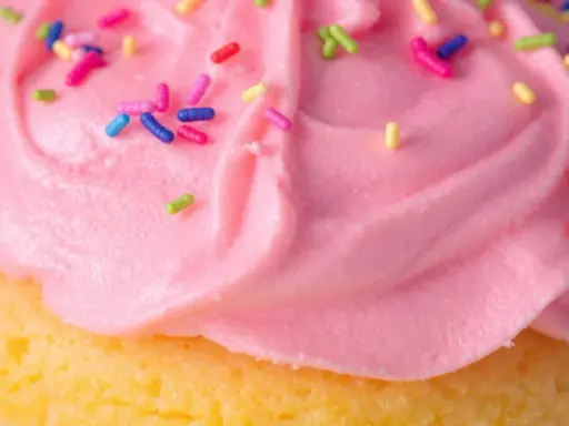Glaçage cupcake sans beurre rose vif, parsemé de vermicelles colorés. Un délice léger et festif !