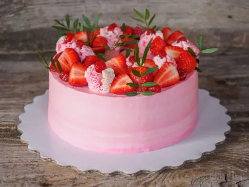 Un délicieux gâteau fraise anniversaire rose, orné de fruits frais et de crème, prêt à célébrer un moment spécial.