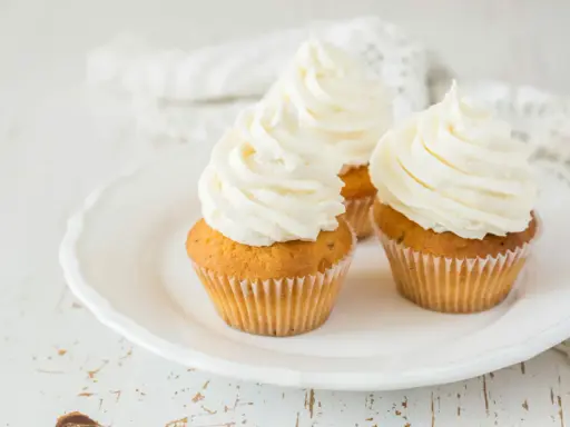 Trois cupcakes sur une assiette blanche, ornés d'un généreux glacage cupcake vanille.