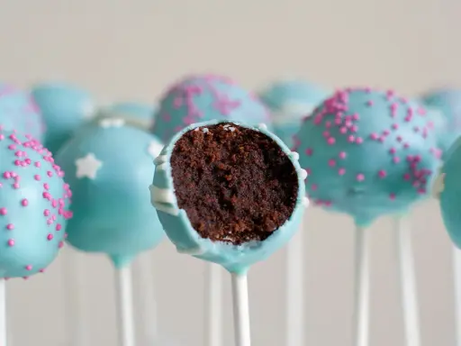 Gourmandes boules de chocolat bleu ciel, décorées de vermicelles roses ou d'étoiles blanches. Une recette facile de cake pop à dévorer !