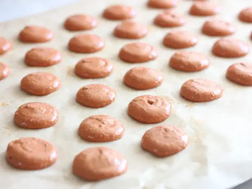 Des petites **collerettes macaron** marron clair, prêtes à être enfournées pour devenir de délicieux macarons.