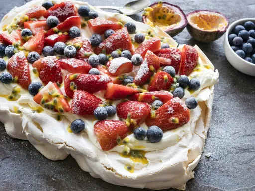 Pavlova inratable garnie de fraises, myrtilles et fruits de la passion. Un délice croustillant à l'extérieur et moelleux à l'intérieur.