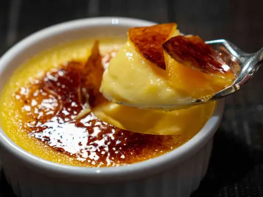 Une cuillère de crème brûlée, parfaite pour savoir que faire avec 4 jaunes d'œufs. La croûte caramélisée craque sous la cuillère.
