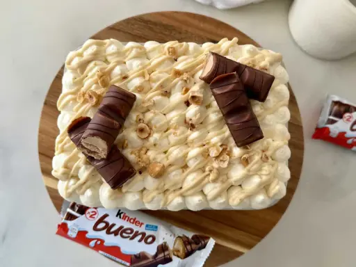 Un délicieux tiramisu Kinder Bueno, garni de morceaux de chocolat et de noisettes concassées. Un vrai régal pour les amateurs de chocolat !