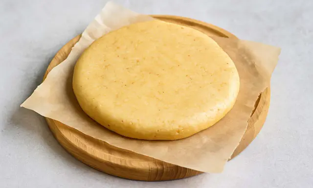 Pâte sablée crue, prête pour la conservation au frigo. Elle repose sur du papier sulfurisé, posé sur une planche en bois.