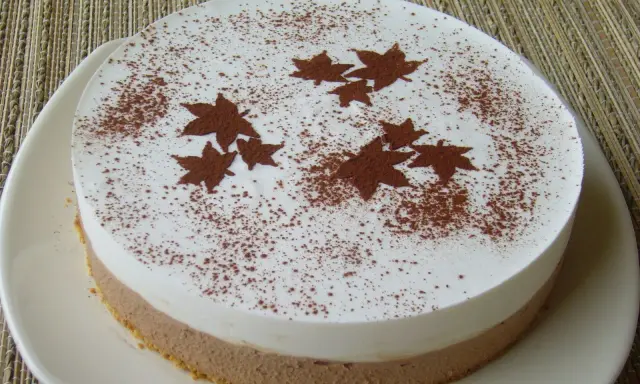 Gâteau bicolore, blanc et chocolat, décoré de feuilles d'automne en cacao. Un dessert léger et gourmand pour célébrer l'automne.