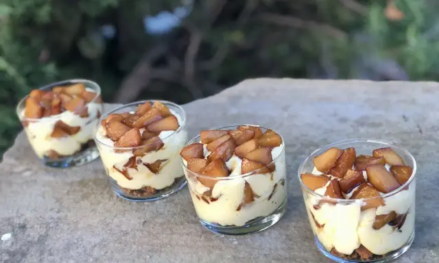 Quatre verrines mascarpone spéculoos, garnies de pommes caramélisées, sur une pierre.