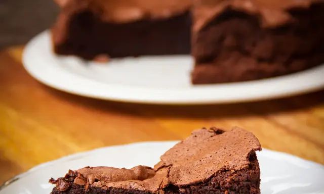 Une part de gâteau au chocolat intense, digne d'un chef pâtissier comme Pierre Hermé, sur une assiette blanche.