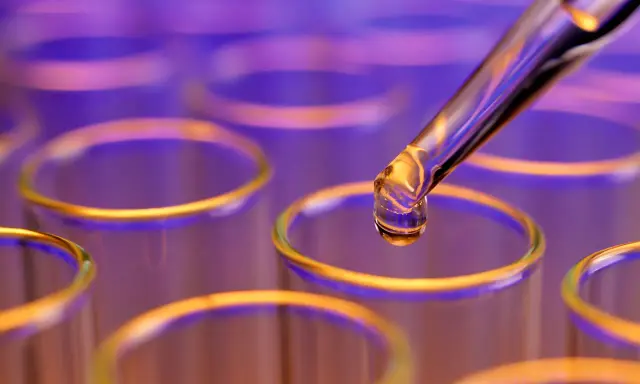 Goutte de colorant alimentaire liquide tombant d'une pipette dans un tube à essai.
