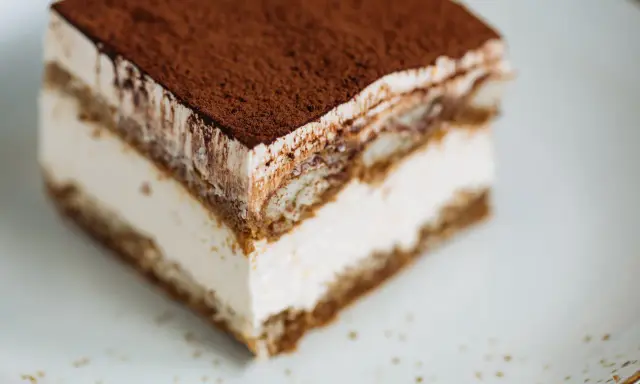Une part de tiramisu onctueux, saupoudrée de cacao, prête à être dégustée. Une recette facile pour un dessert parfait.