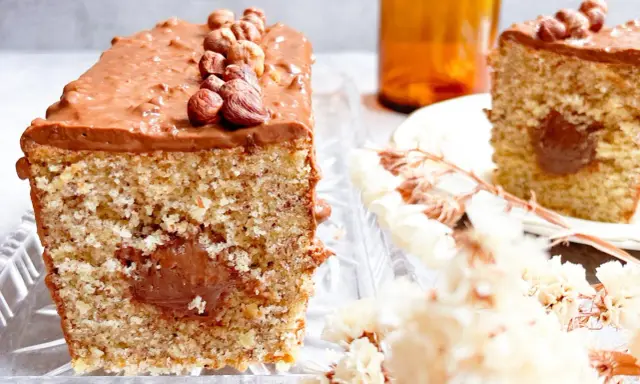 Gâteau moelleux avec un cœur coulant et un glaçage Nutella généreux, décoré de noisettes entières.