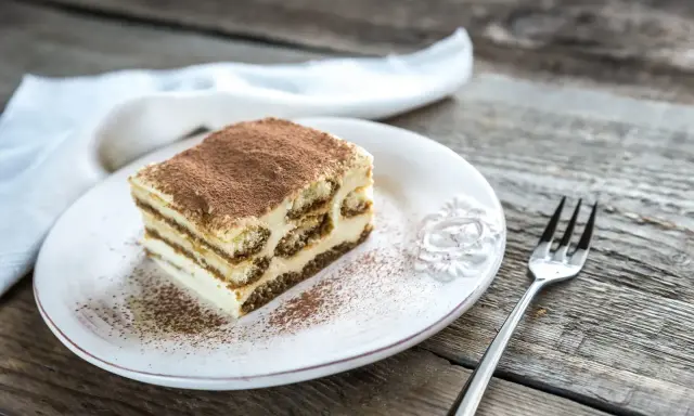 Une part de tiramisu sur une assiette blanche, saupoudrée de cacao. Combien de temps au frigo pour ce délice ?