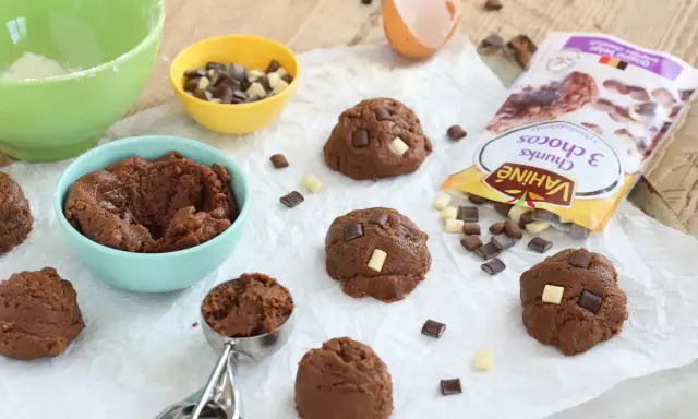 Pâte à cookies au chocolat prête à être façonnée. Des pépites de chocolat et un sachet "comment faire des pépites de chocolat" sont à proximité.