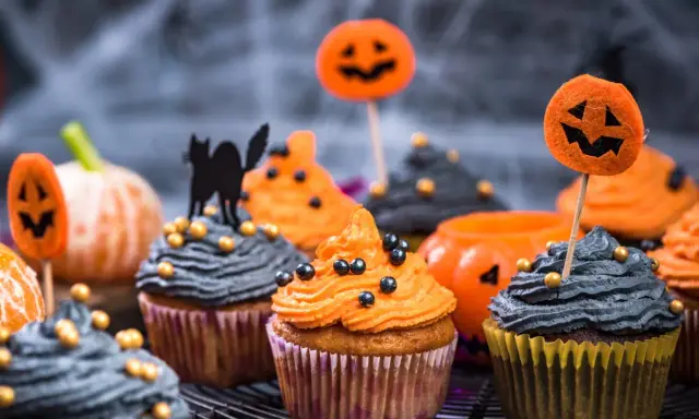 Cupcakes d'Halloween faciles décorés de glaçage orange et gris, de citrouilles et d'un chat noir. Parfait pour une fête effrayante !