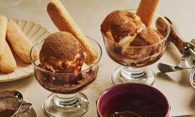 Deux coupes de glace tiramisu, saupoudrées de cacao, avec des biscuits à la cuillère. Un délice glacé à savourer.